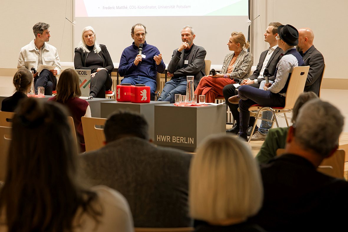 8 Personen auf einem Podium, im Hintergrund eine Präsentation zu BECOIL © Manfred H. Vogel