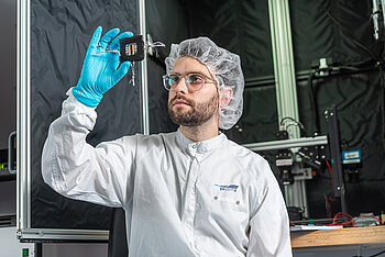 Student in Laborkleidung inspiziert eine Solarzelle