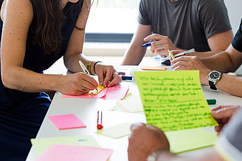 Jemand schreibt etwas bei einer Teamarbeit auf Kärtchen © HTW Berlin/Nikolas Fahlbusch