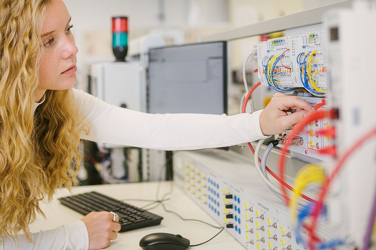 Eine Studentin arbeitet im Labor mit Kabeln und Schaltern