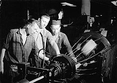 Die Brigade Fritz Ploen arbeitet an einer Maschine im Kabelwerk Oberspree, Foto von ca. 1959Arbeiter im Kabelwerk Oberspree, Foto von ca. 1959 © Bundesarchiv