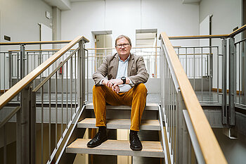 Oliver Rump sitzt auf einer Treppe